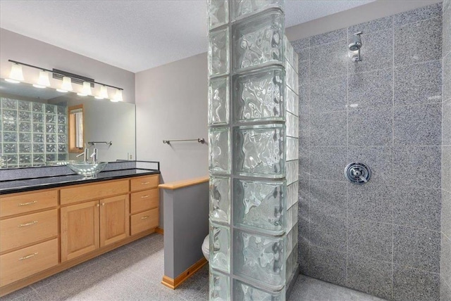 bathroom featuring vanity, a textured ceiling, baseboards, and walk in shower