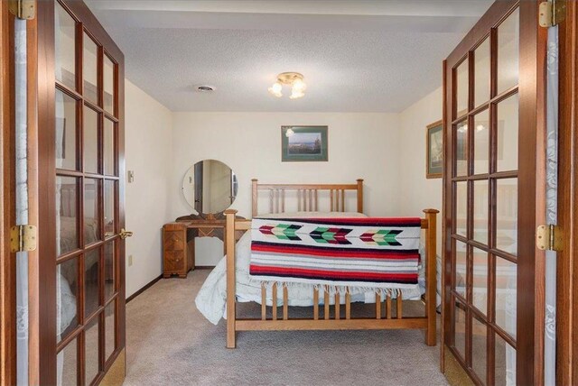 carpeted bedroom with french doors, a textured ceiling, and baseboards