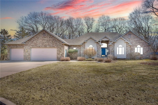 view of front of property featuring roof with shingles, a lawn, driveway, stone siding, and an attached garage