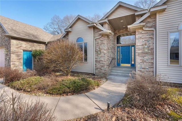 property entrance with brick siding and a garage