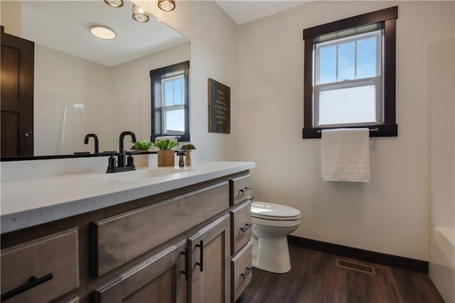 3557 114th St, Chippewa Falls, WI 54729 - bathroom with toilet, wood finished floors, vanity, baseboards, and visible vents