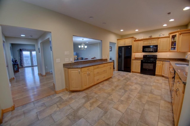 kitchen with dark countertops, recessed lighting, an inviting chandelier, black appliances, and a sink