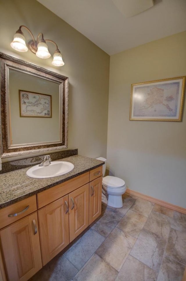 bathroom with baseboards, toilet, and vanity