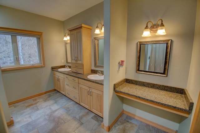 bathroom with double vanity, baseboards, and a sink