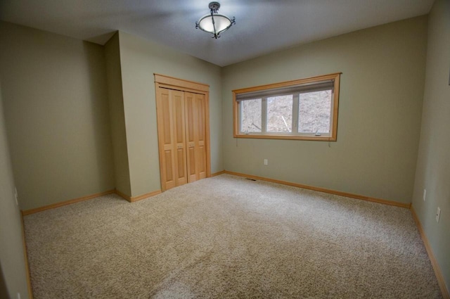 unfurnished bedroom with a closet, baseboards, and carpet