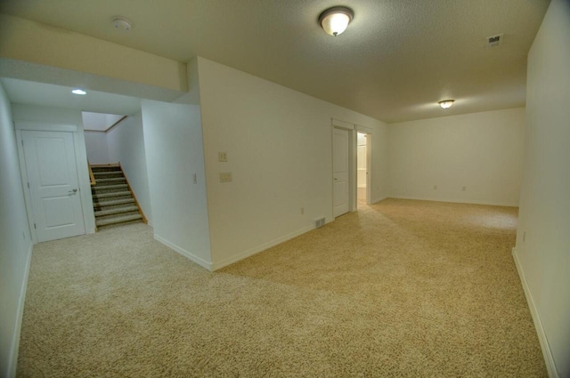 unfurnished room featuring stairway, carpet, baseboards, and a textured ceiling