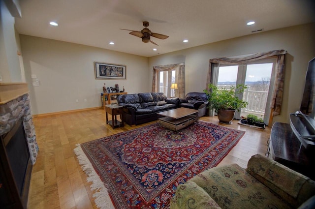 living room with recessed lighting, light wood-style flooring, a stone fireplace, and ceiling fan