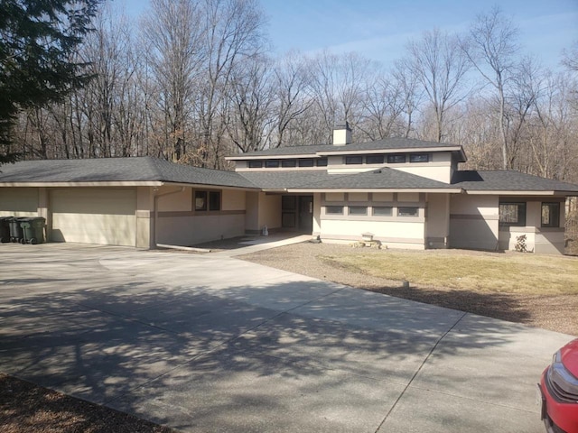 prairie-style home featuring stucco siding, a front yard, roof with shingles, and driveway