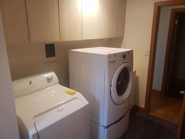 laundry area featuring washer and clothes dryer, visible vents, and cabinet space