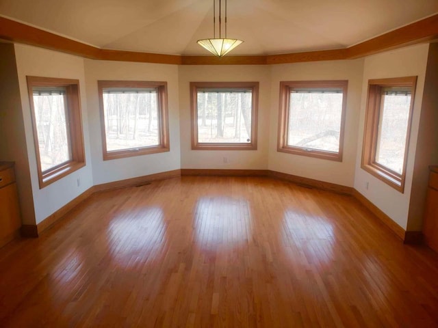 unfurnished room featuring light wood-type flooring, plenty of natural light, baseboards, and vaulted ceiling