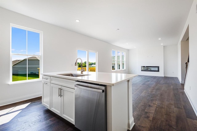 kitchen featuring a kitchen island with sink, dark wood finished floors, stainless steel dishwasher, white cabinets, and a sink