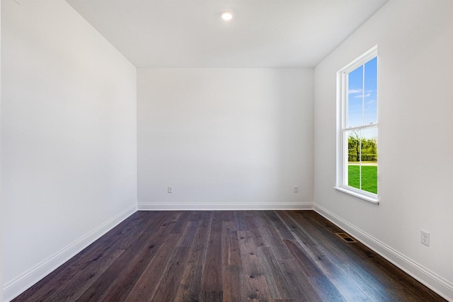 unfurnished room with visible vents, baseboards, and dark wood finished floors