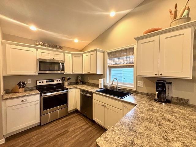 kitchen featuring lofted ceiling, appliances with stainless steel finishes, dark wood-style floors, white cabinets, and a sink