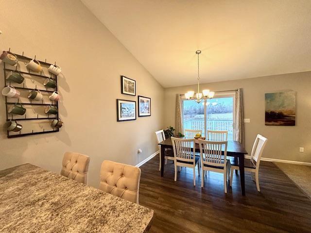 dining area featuring dark wood finished floors, vaulted ceiling, baseboards, and a chandelier