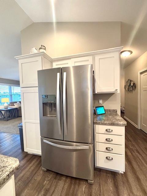 kitchen with vaulted ceiling, dark wood finished floors, stainless steel fridge with ice dispenser, and white cabinetry