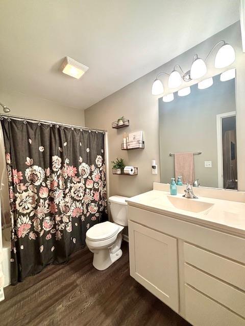 bathroom with toilet, wood finished floors, and vanity