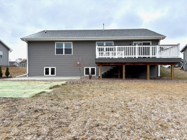 back of property with a deck, stairway, and a shingled roof