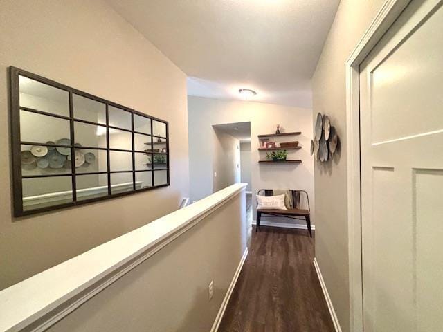 corridor featuring dark wood-style floors, an upstairs landing, and baseboards