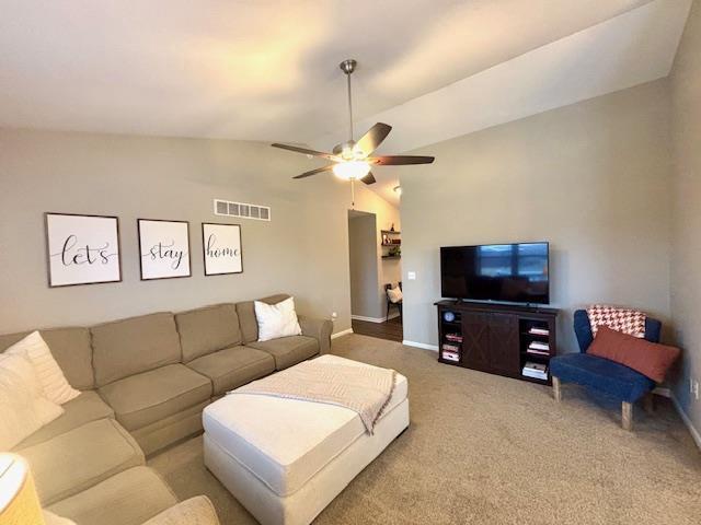 carpeted living room featuring visible vents, lofted ceiling, baseboards, and a ceiling fan