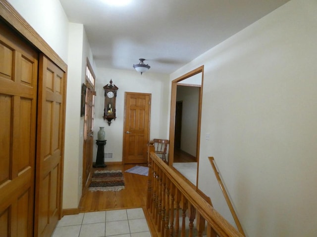 hall with light tile patterned flooring and an upstairs landing