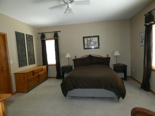 bedroom with light colored carpet, a ceiling fan, and baseboards