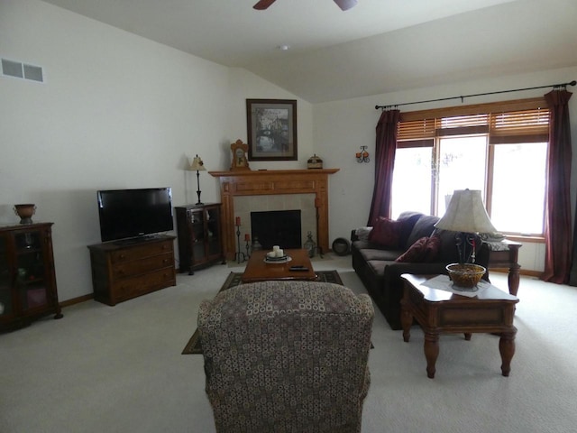 carpeted living room with a fireplace, vaulted ceiling, a ceiling fan, and visible vents