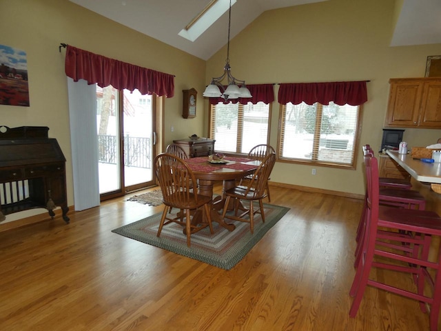 dining space with a wealth of natural light, light wood-style flooring, and vaulted ceiling with skylight