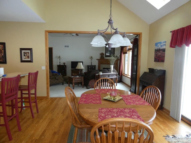 dining space featuring a chandelier, visible vents, light wood finished floors, and lofted ceiling