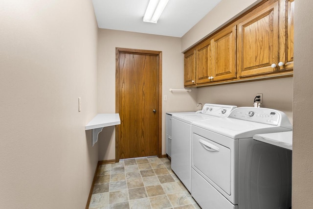 clothes washing area with baseboards, cabinet space, and washing machine and clothes dryer