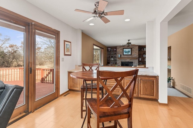 dining room with light wood finished floors, visible vents, recessed lighting, a fireplace, and a ceiling fan