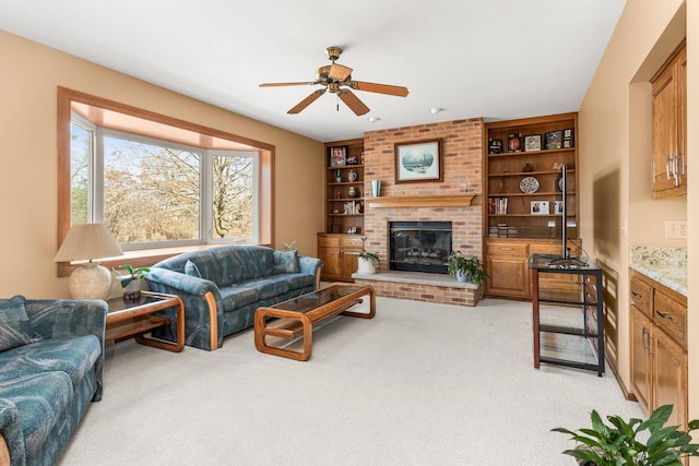 living room with a brick fireplace, built in features, a ceiling fan, and light carpet