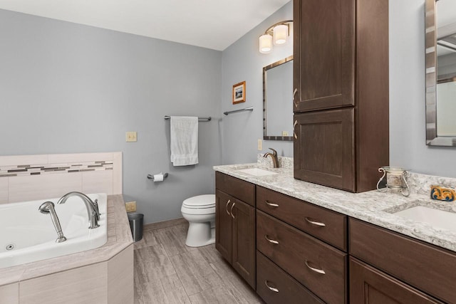 bathroom featuring double vanity, a whirlpool tub, toilet, and a sink