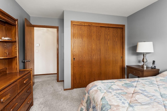 carpeted bedroom with a closet and baseboards