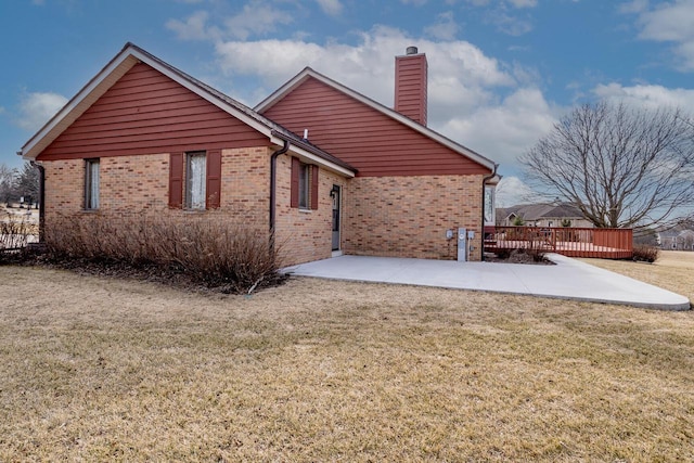 rear view of house featuring a patio area, a deck, a lawn, and brick siding