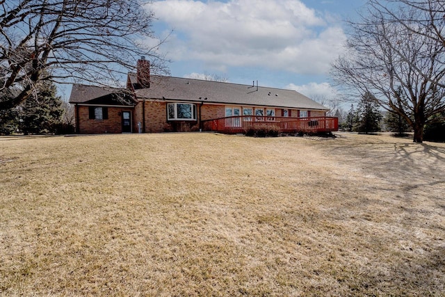 rear view of property with a lawn, a chimney, and a deck