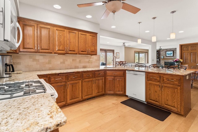 kitchen with white appliances, brown cabinetry, light wood-type flooring, and ceiling fan