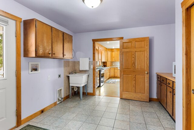 N402 24th Ave, Neshkoro, WI 54960 - clothes washing area with hookup for an electric dryer, light tile patterned floors, hookup for a washing machine, baseboards, and cabinet space
