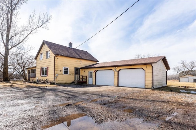 view of property exterior with a garage, driveway, and a chimney