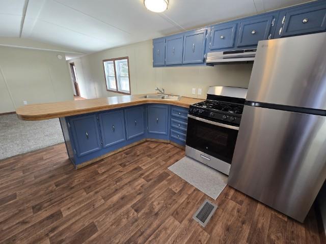 W5029 N Pathfinder Cir, Shawano, WI 54166 - kitchen with blue cabinetry, under cabinet range hood, a peninsula, stainless steel appliances, and a sink