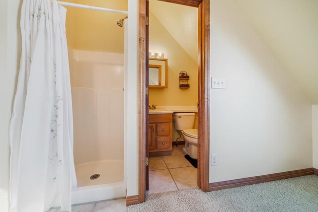 bathroom featuring tile patterned flooring, baseboards, toilet, a stall shower, and vanity