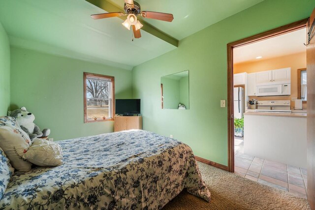 carpeted bedroom featuring tile patterned flooring, baseboards, freestanding refrigerator, and ceiling fan