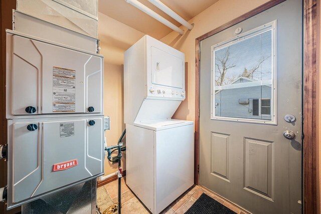 laundry room with light tile patterned floors, heating unit, laundry area, and stacked washing maching and dryer