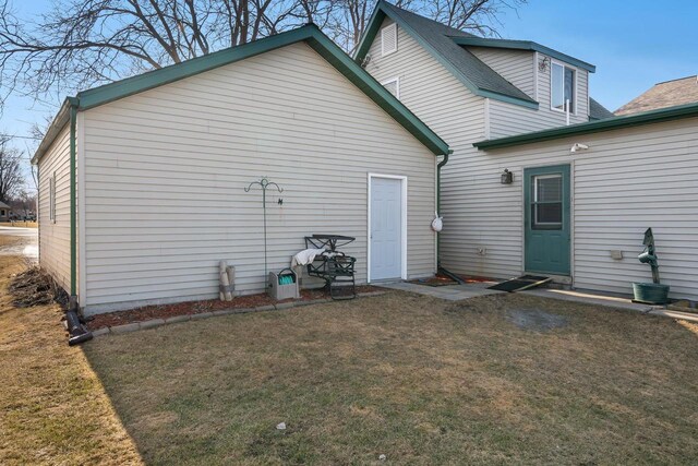 back of property with a yard and roof with shingles