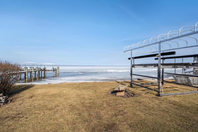 dock area featuring a beach view, a lawn, and a water view