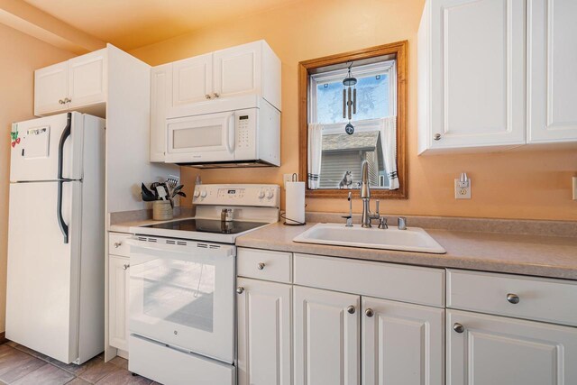kitchen with white cabinets, white appliances, light countertops, and a sink
