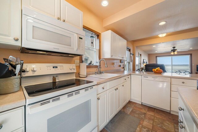 kitchen featuring a sink, white appliances, ceiling fan, and light countertops