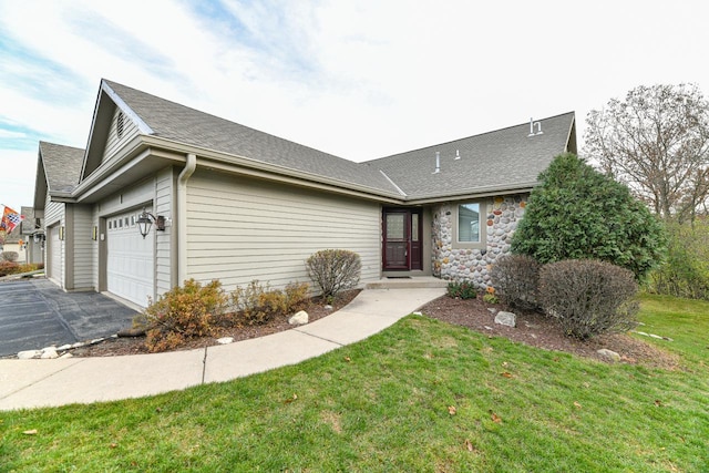 view of front of home featuring a front lawn, driveway, a garage, and roof with shingles