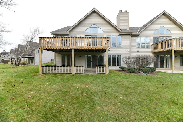 back of property featuring a patio area, a lawn, a chimney, and a deck