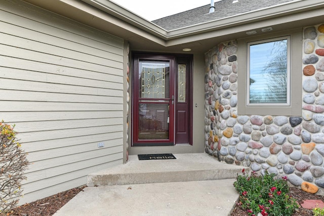 property entrance with stone siding and a shingled roof