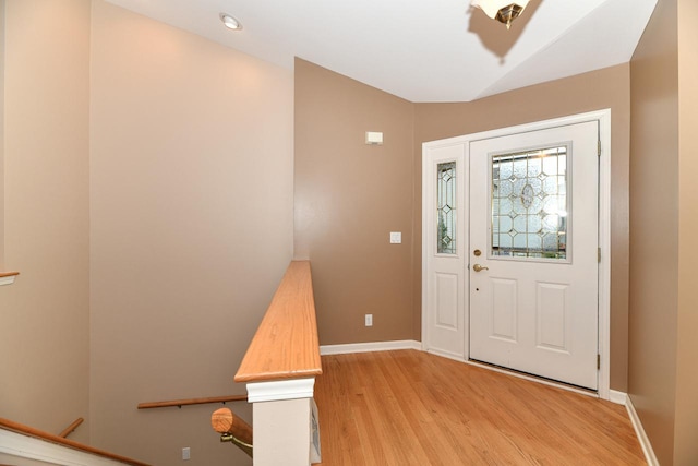 entryway featuring baseboards, light wood-style floors, and vaulted ceiling